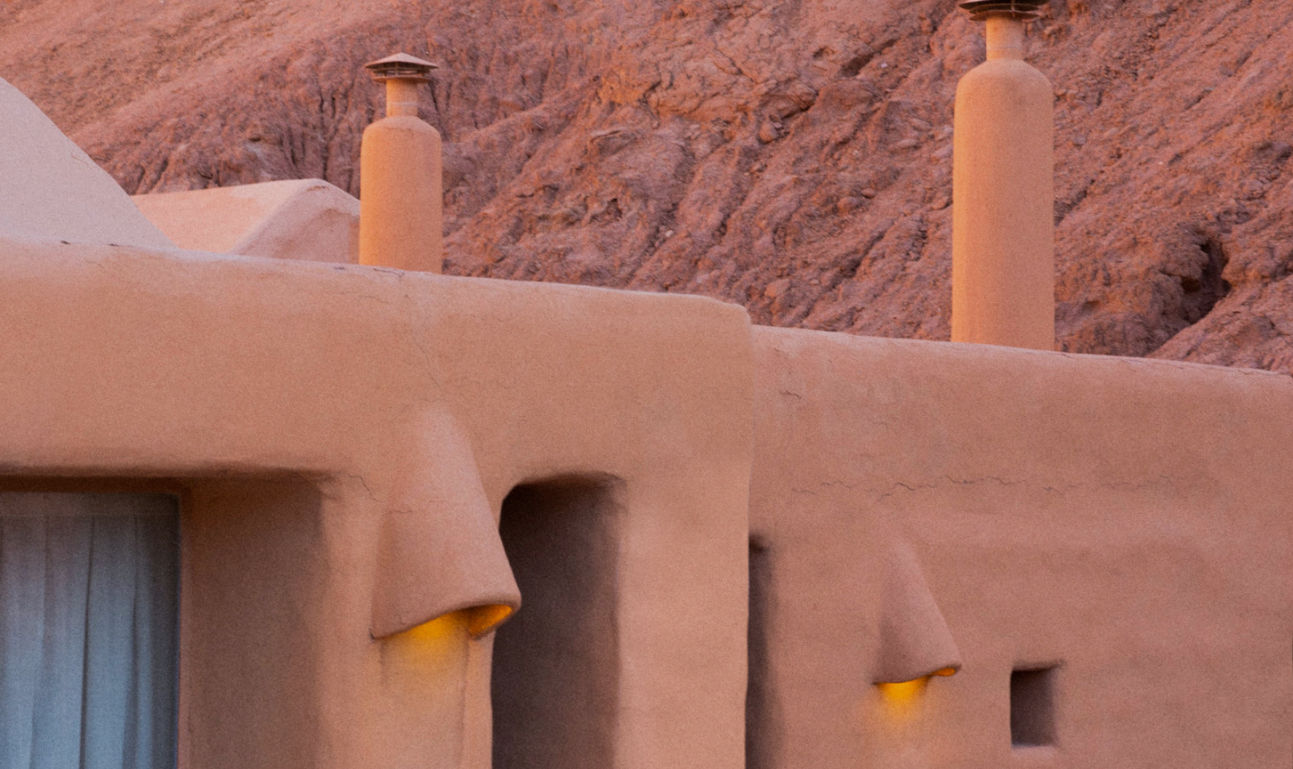 Adobe-style buildings glowing at dusk against a desert hillside