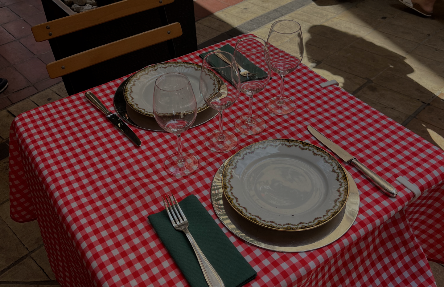 Outdoor table set with a red gingham cloth and wine glasses